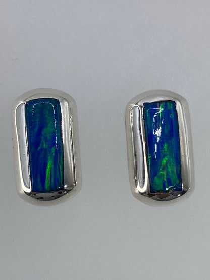 Vista frontal de los aretes mostrando el brillo y los tonos verdes y azules del ópalo
