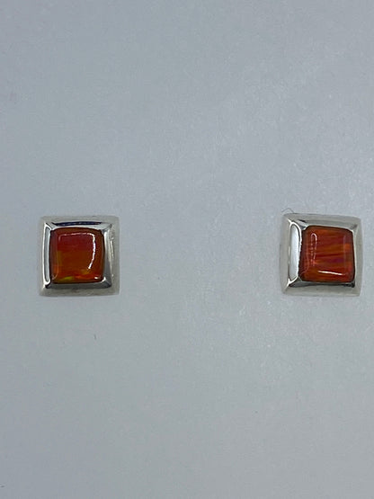 Vista frontal de aretes delicados de plata con piedra ópalo naranja