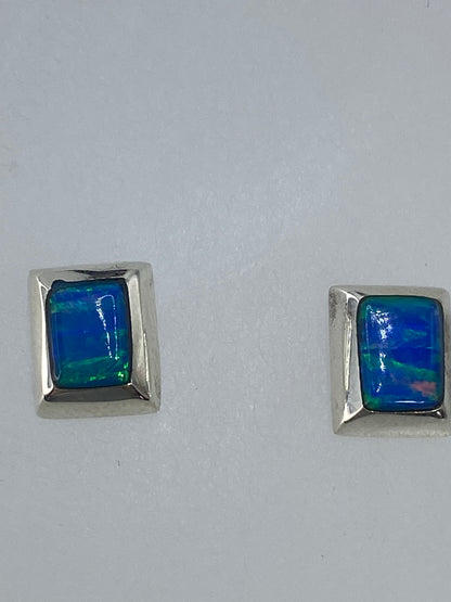 Aretes sobre paño blanco mostrando el brillo y profundidad del ópalo