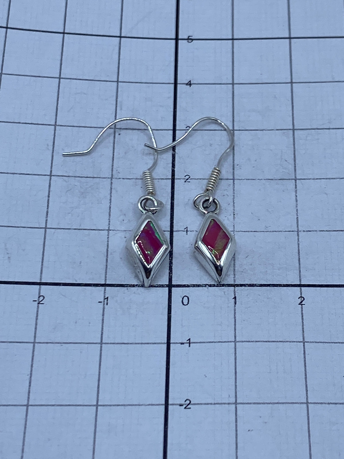 Aretes sobre regla de centímetros mostrando el largo de 3.1 cm del par