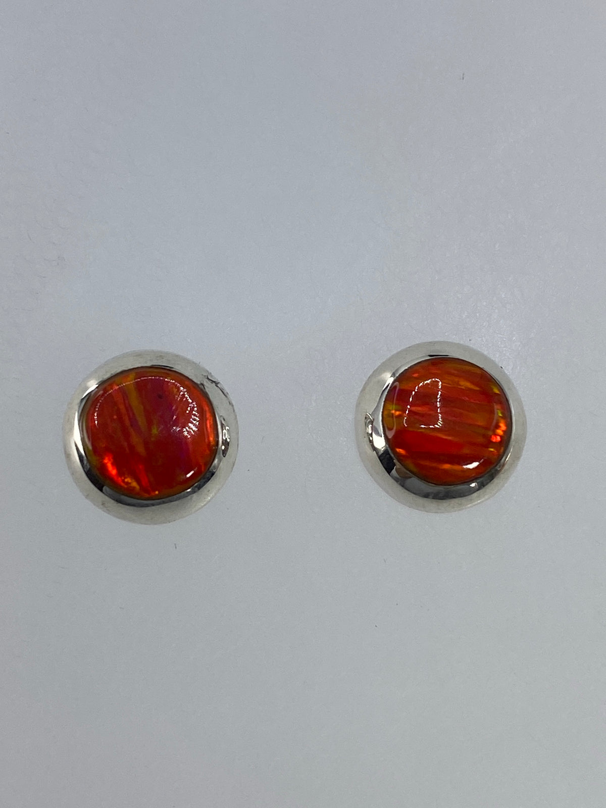 Detalle del ópalo de fuego naranja con juegos de luz dorado en el arete izquierdo