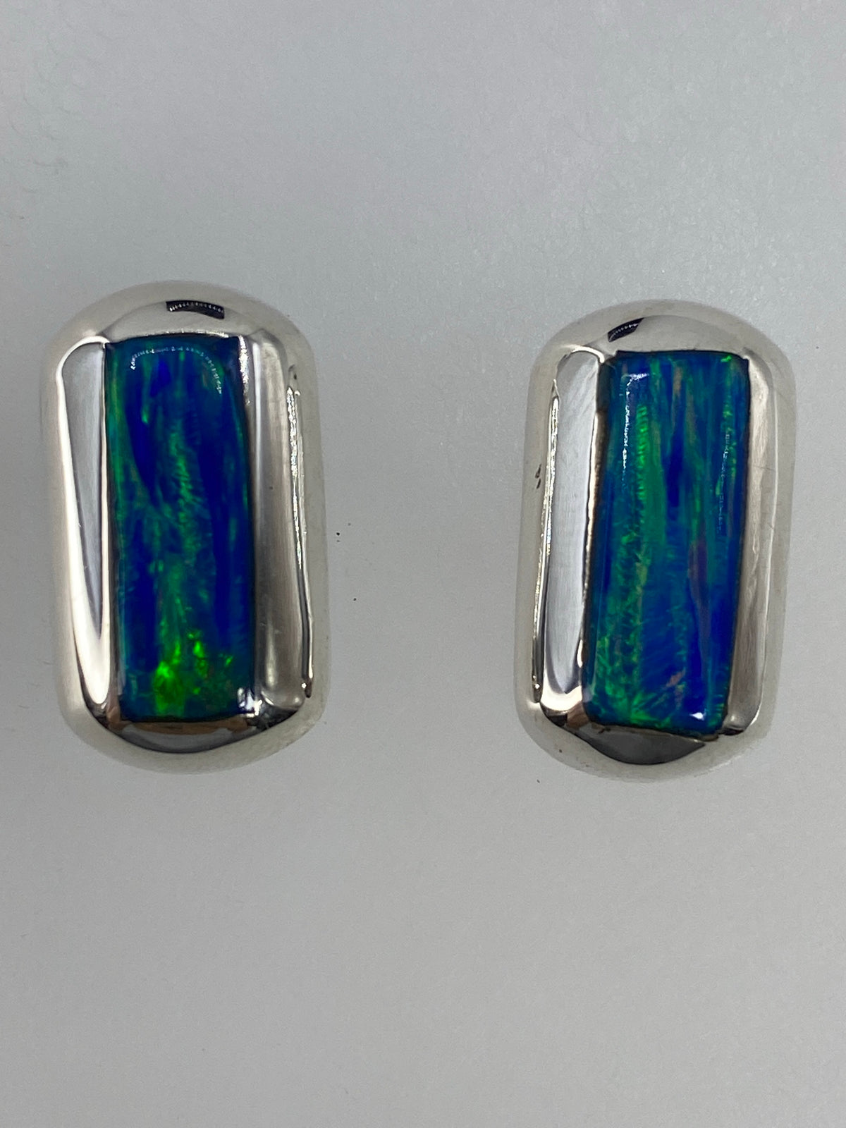 Arete individual de plata con Ópalo de Fuego sobre fondo blanco, detalle del engaste a mano