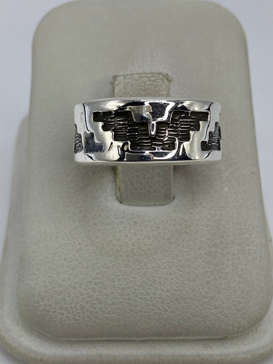 Anillo de plata repujado con diseño geométrico prehispánico en la mano de una persona