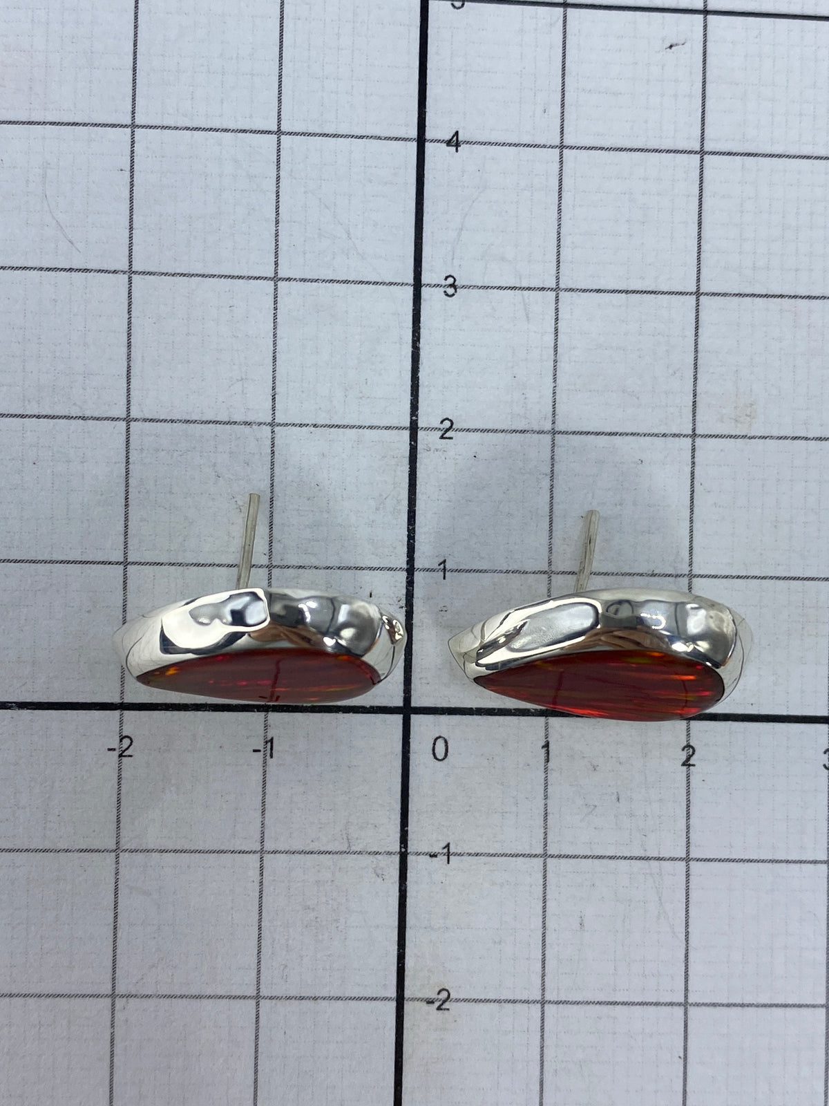 Los aretes sobre fondo blanco demostrando tamaño compacto de 1.3 cm
