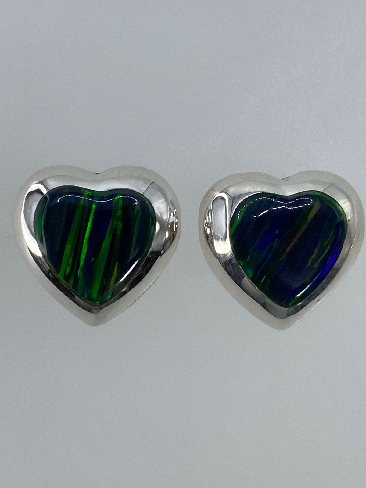Par de aretes de plata con ópalo de fuego verde translúcido en fondo blanco