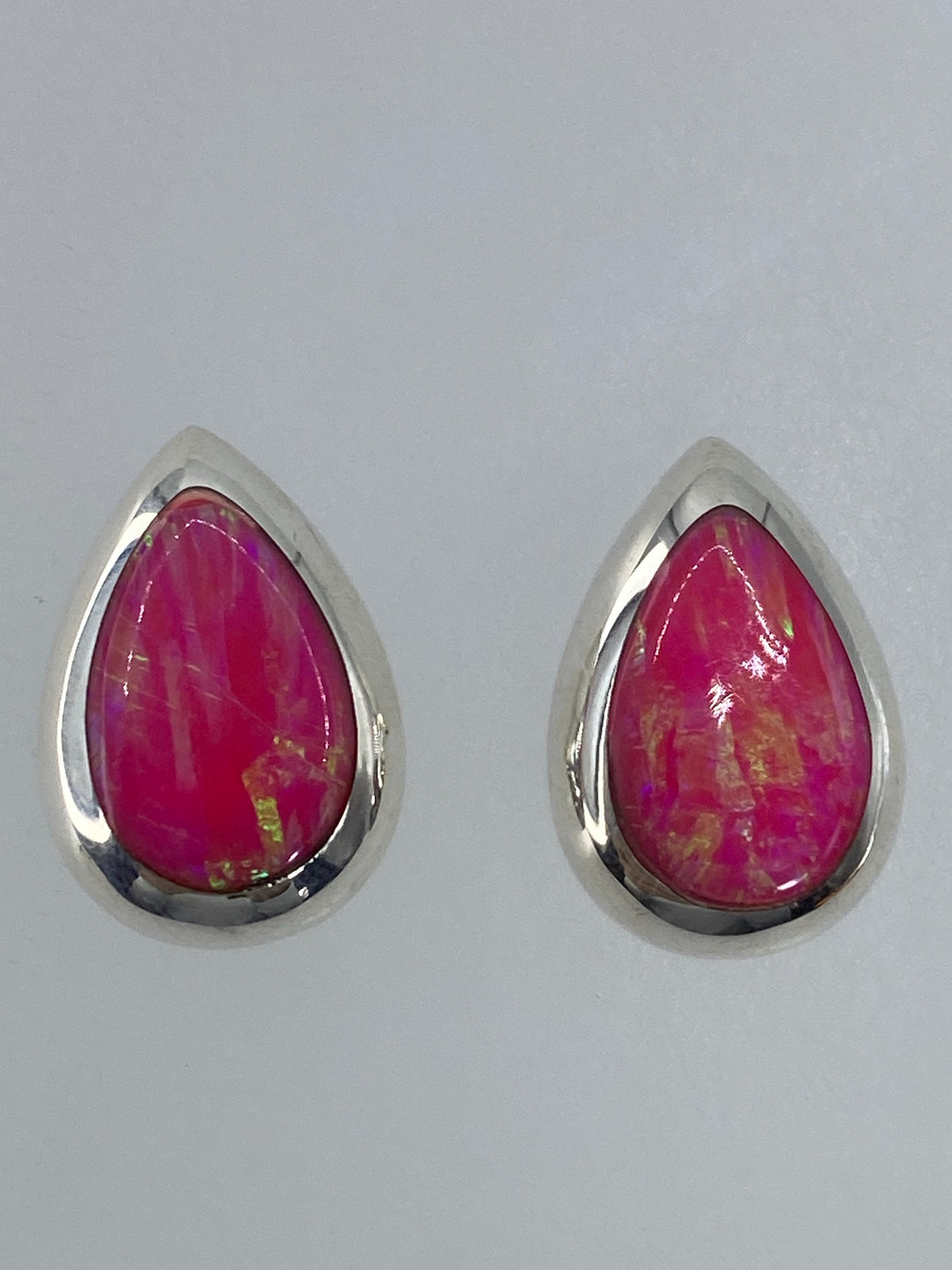 Par de aretes de plata con ópalo de fuego multicolor, vista frontal sobre fondo blanco