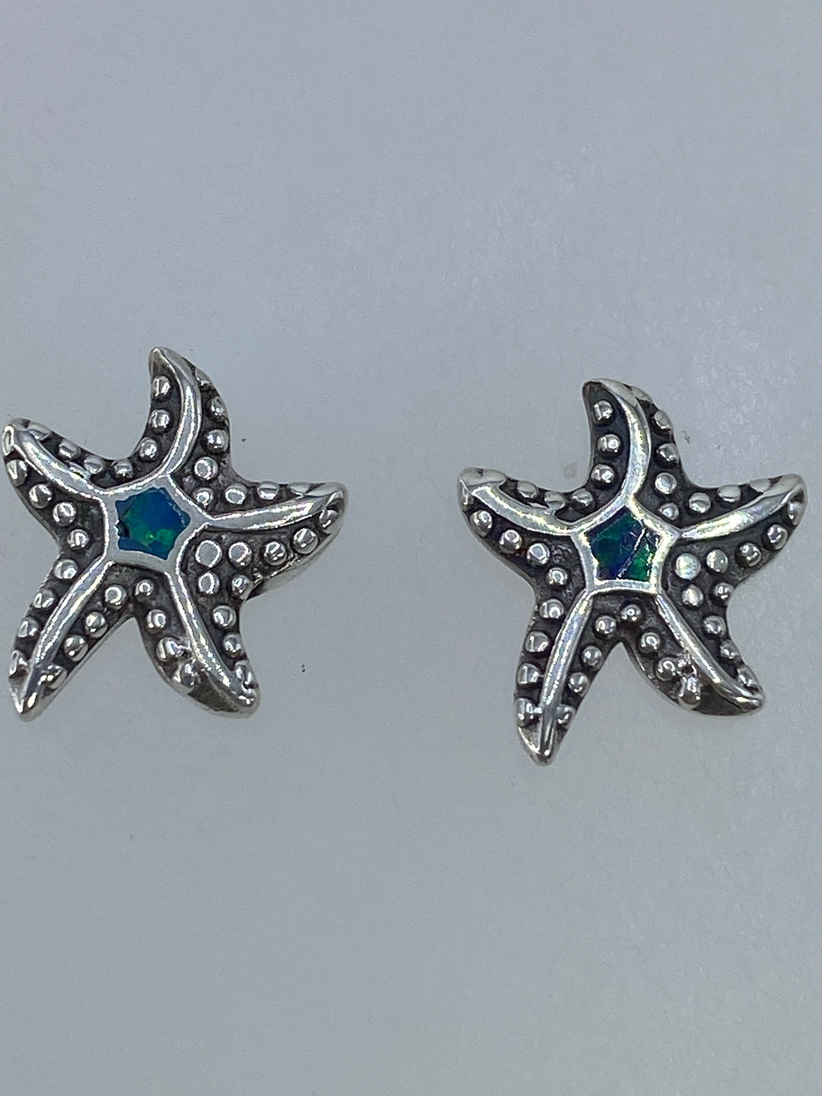 Aretes en miniatura con postes de plata, junto a escala de medidas en centímetros