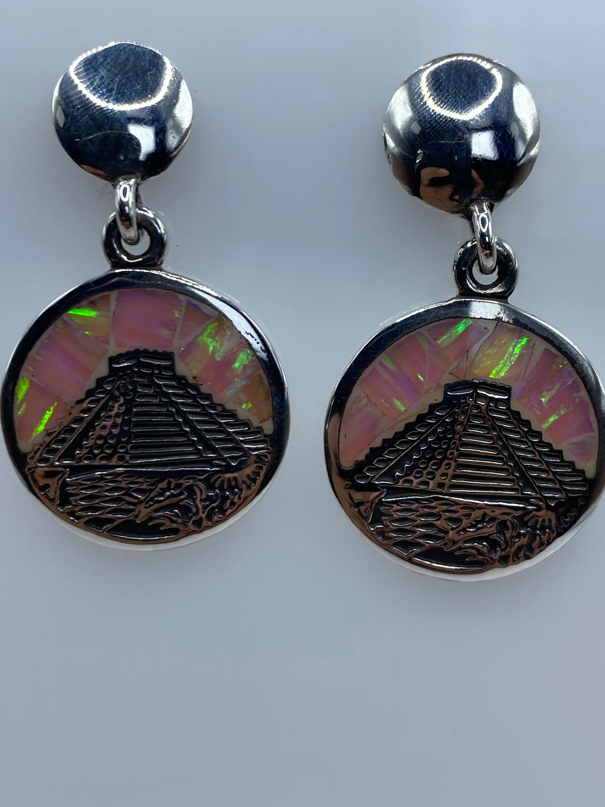 Aretes colgando, mostrando el relieve de la pirámide y el brillo iridiscente del ópalo