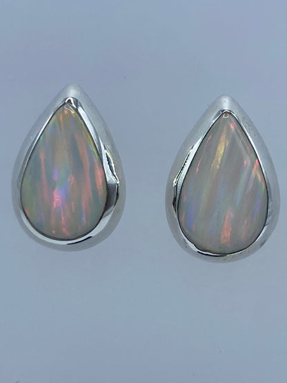 Par de aretes de plata con ópalo de fuego, mostrando reflejos multicolor rojo y naranja