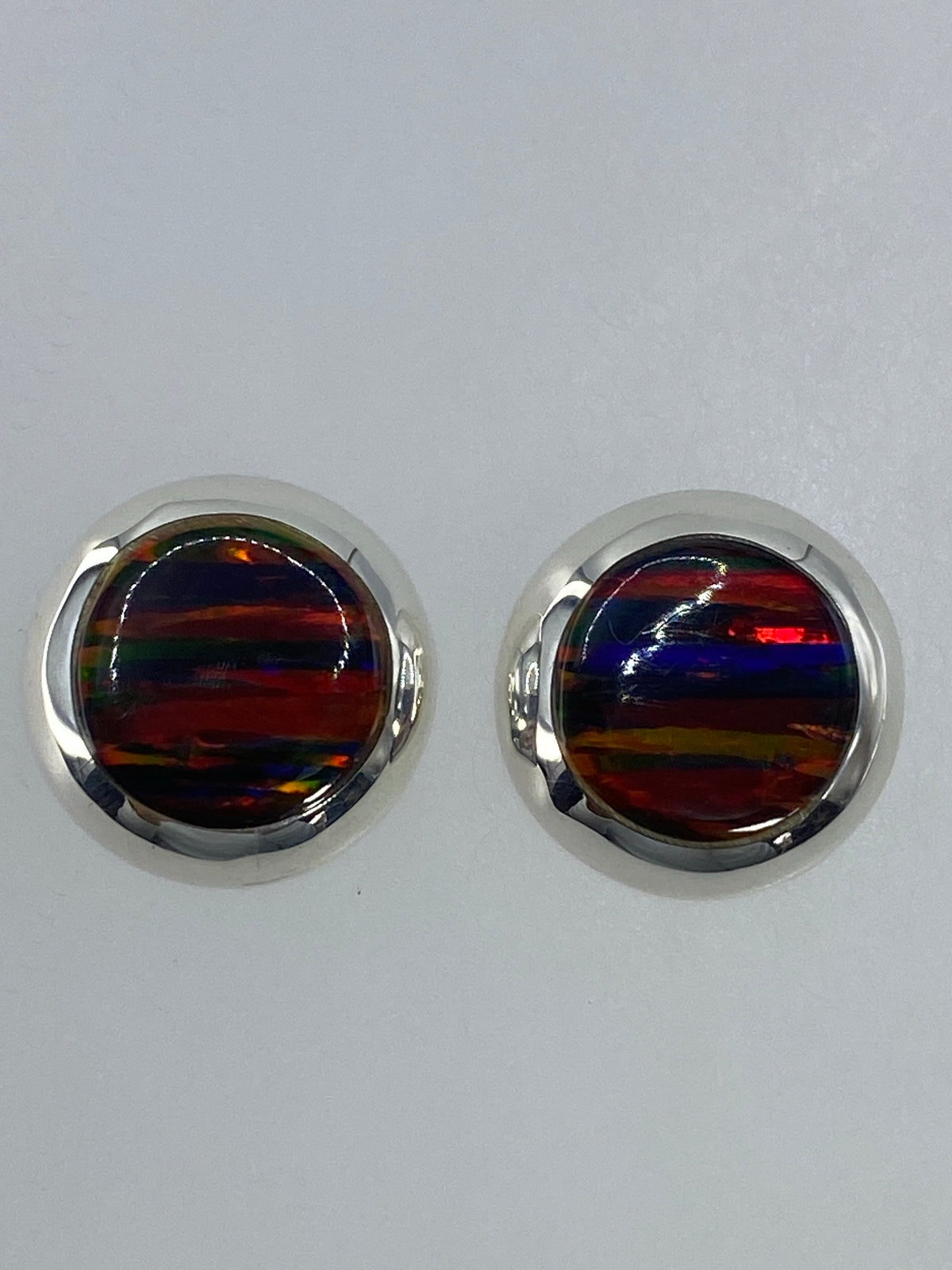 Par de aretes de plata con ópalo de fuego multicolor, vista frontal mostrando los tonos rojos, verdes y azules