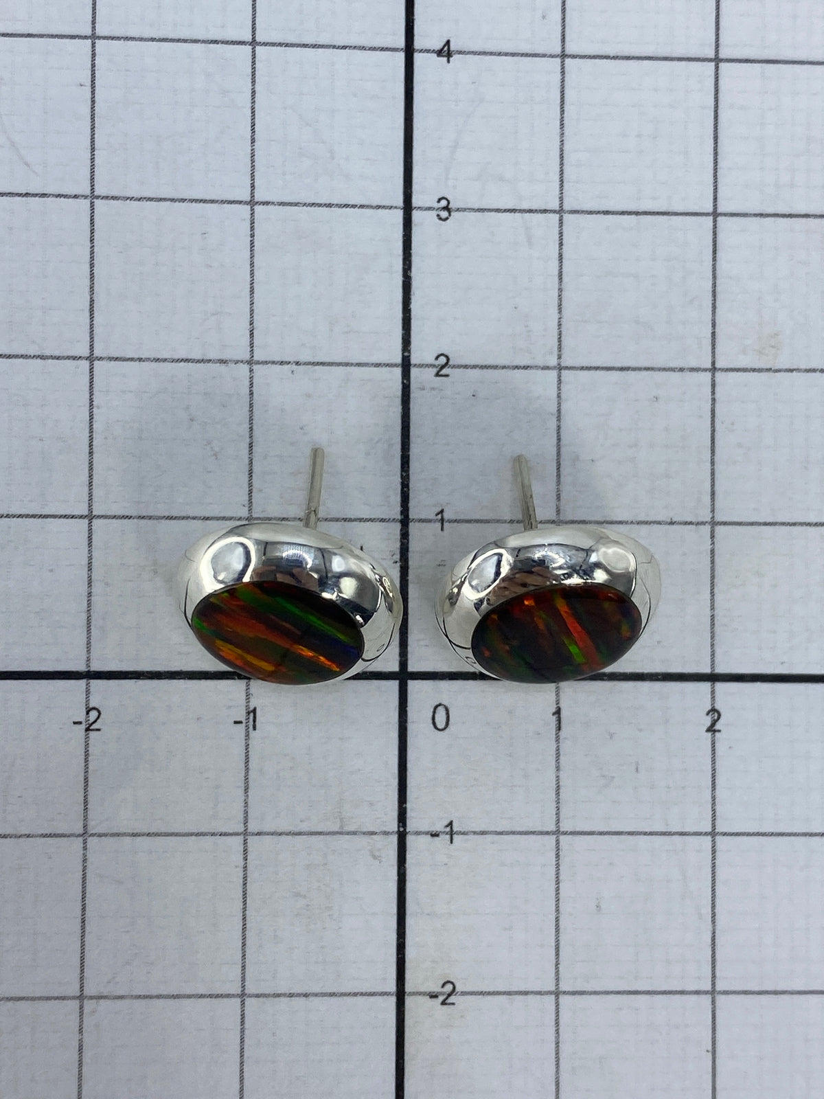 Aretes en uso, vista de cerca sobre la oreja mostrando la iridiscencia del ópalo