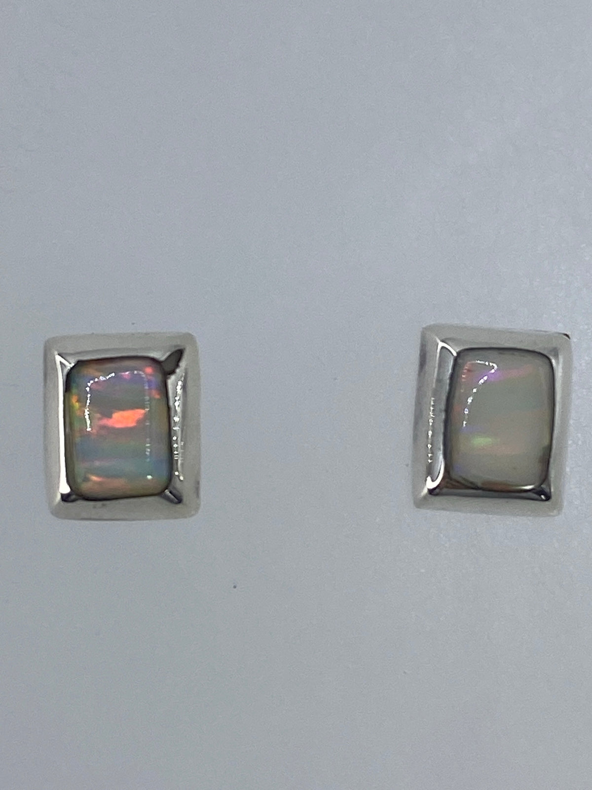 Par de aretes de plata con ópalo de fuego multicolor, mostrando tonos de naranja, rojo y verde