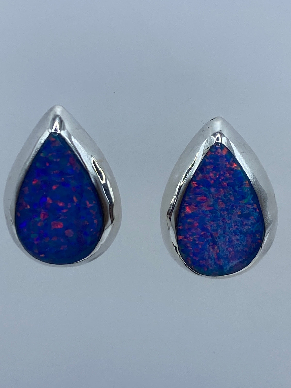 Detalle frontal de un arete mostrando el Ópalo de Fuego con reflejos azules