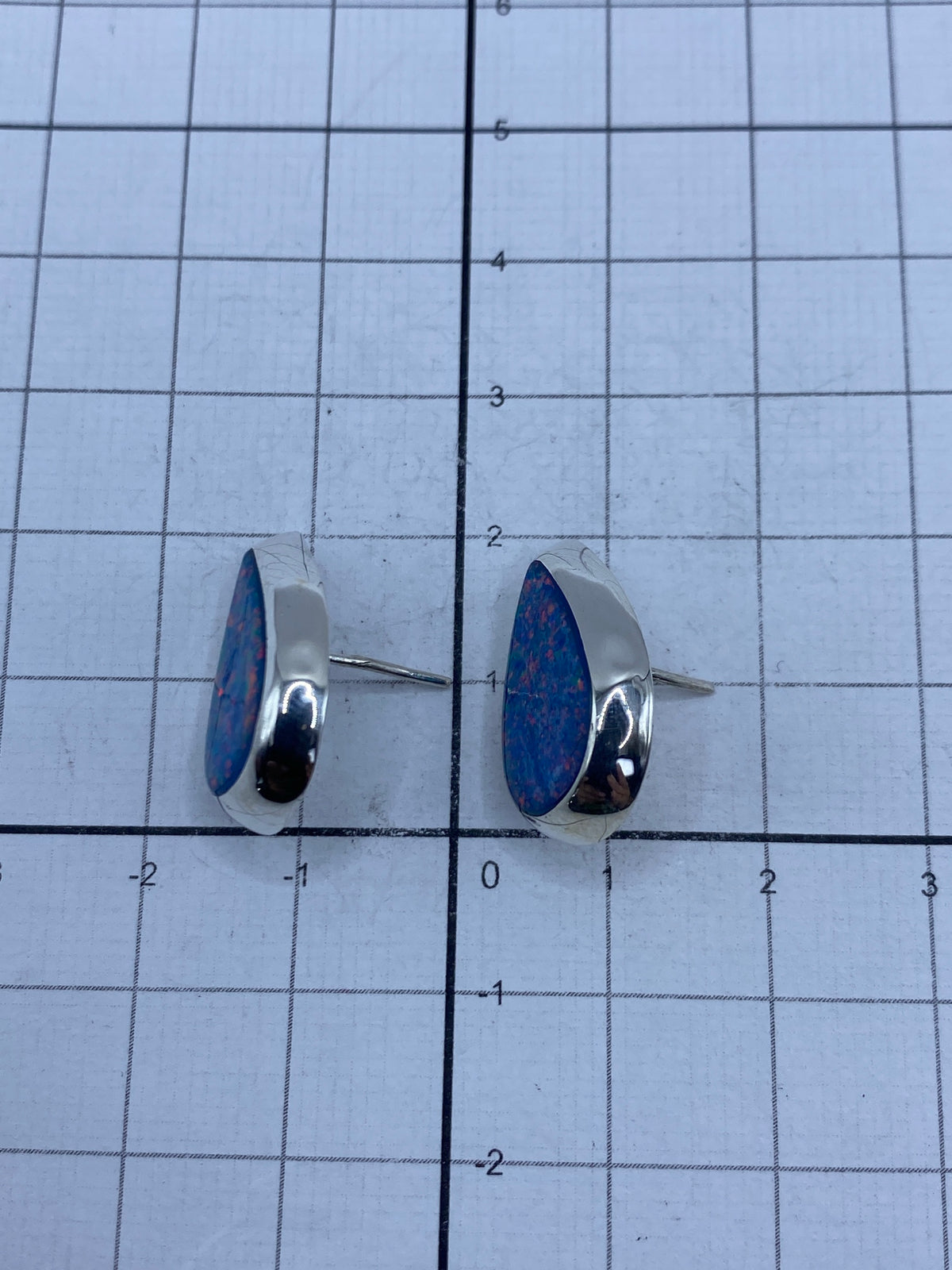 Aretes sobre fondo neutro destacando su tamaño compacto de 2 cm