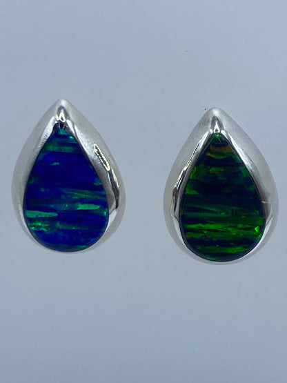 Detalle frontal de arete de plata 925 con ópalo de fuego engastado, luz reflejada en la piedra