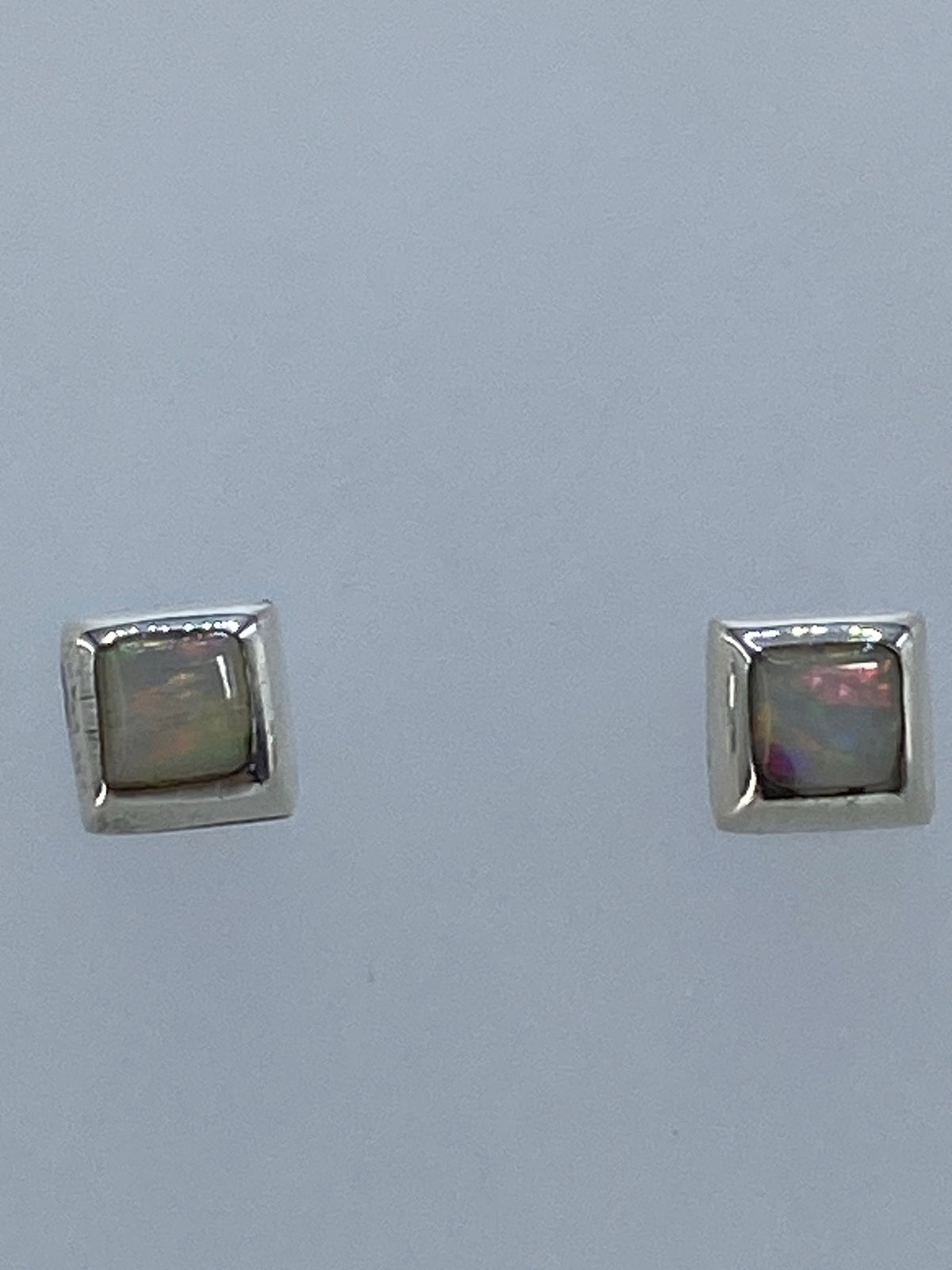Par de aretes de plata con ópalo de fuego multicolor sobre fondo gris