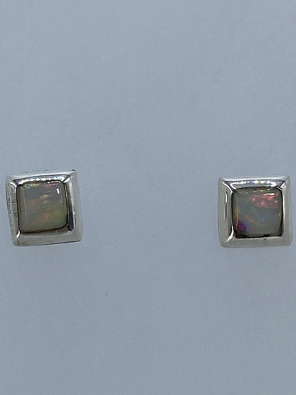 Detalle frontal de los aretes mostrando el juego de colores del ópalo de fuego