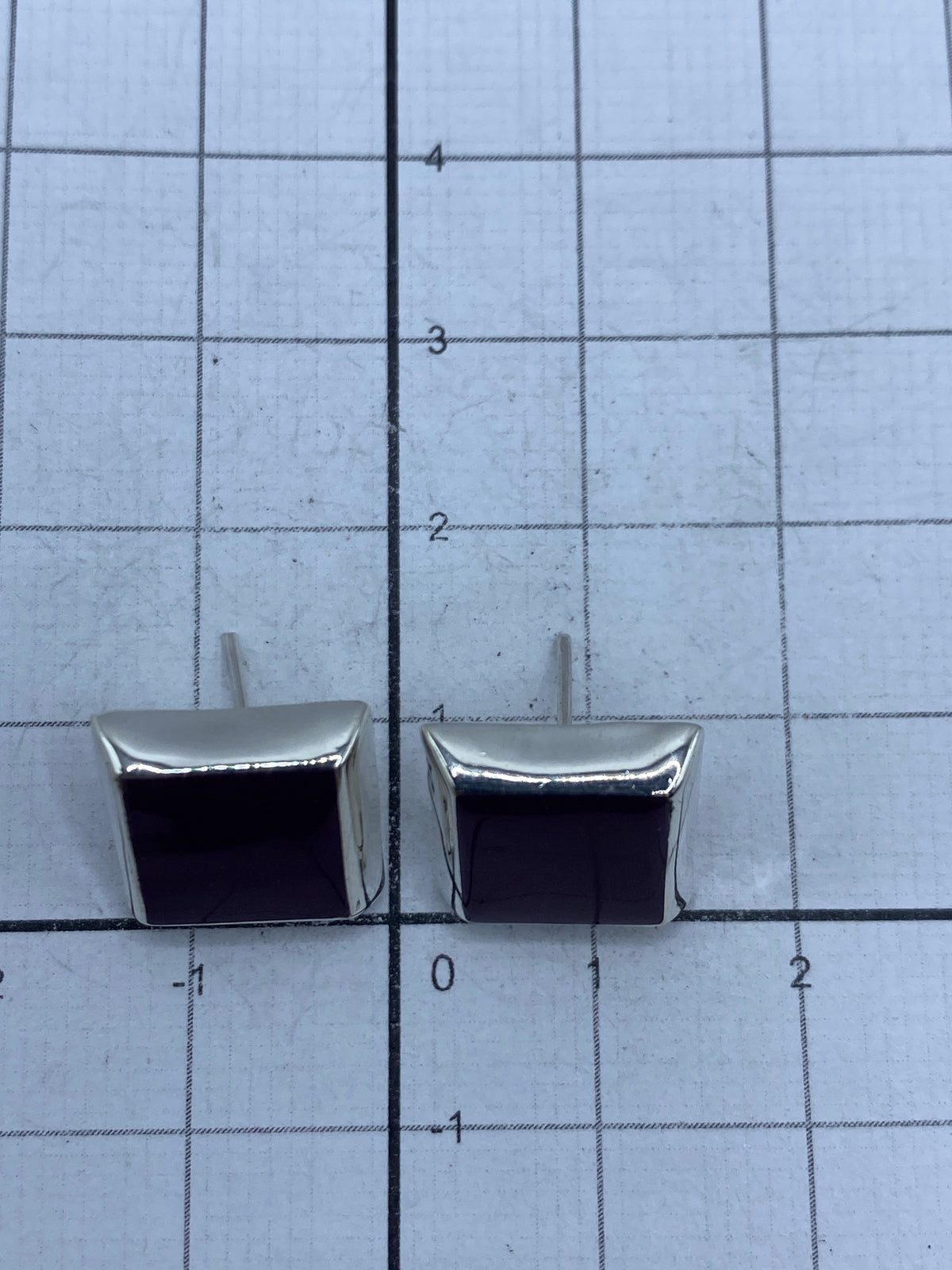 Aretes de perfil destacando el tamaño discreto y la profundidad del color morada