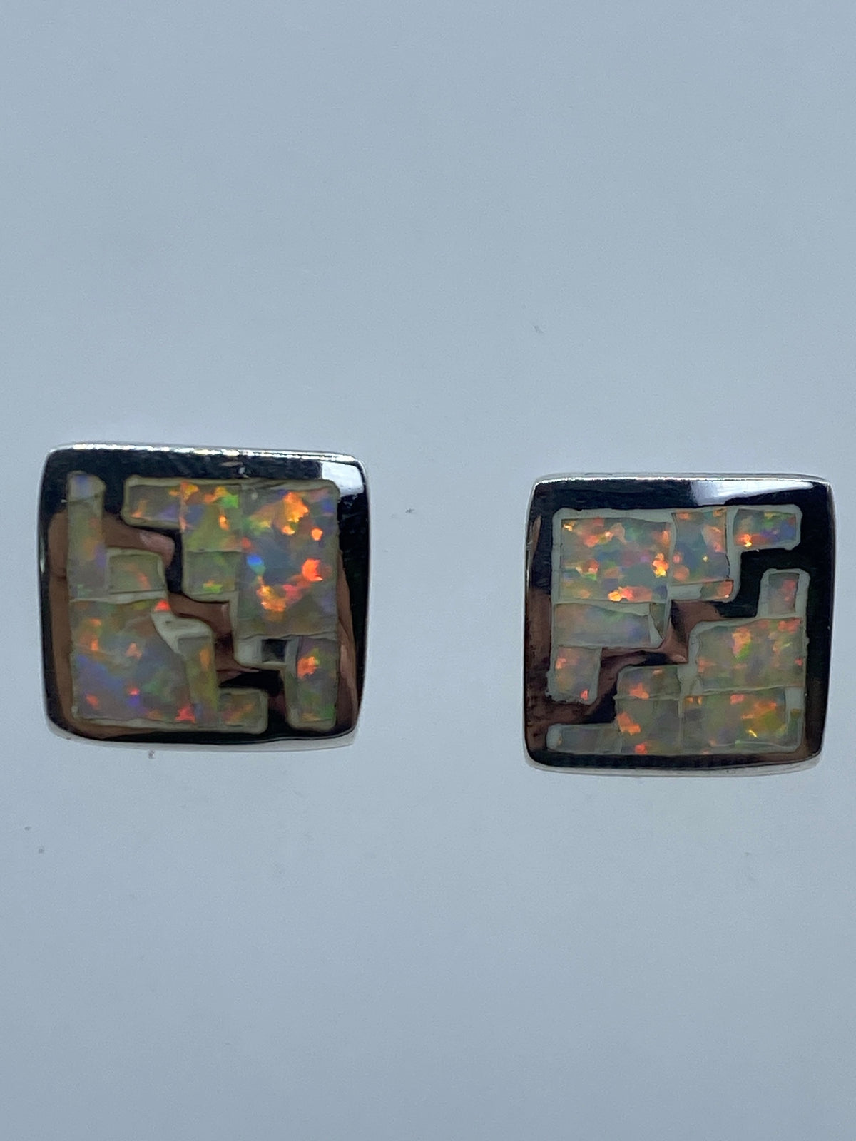 Detalle del engaste manual del ópalo de fuego en los aretes de plata