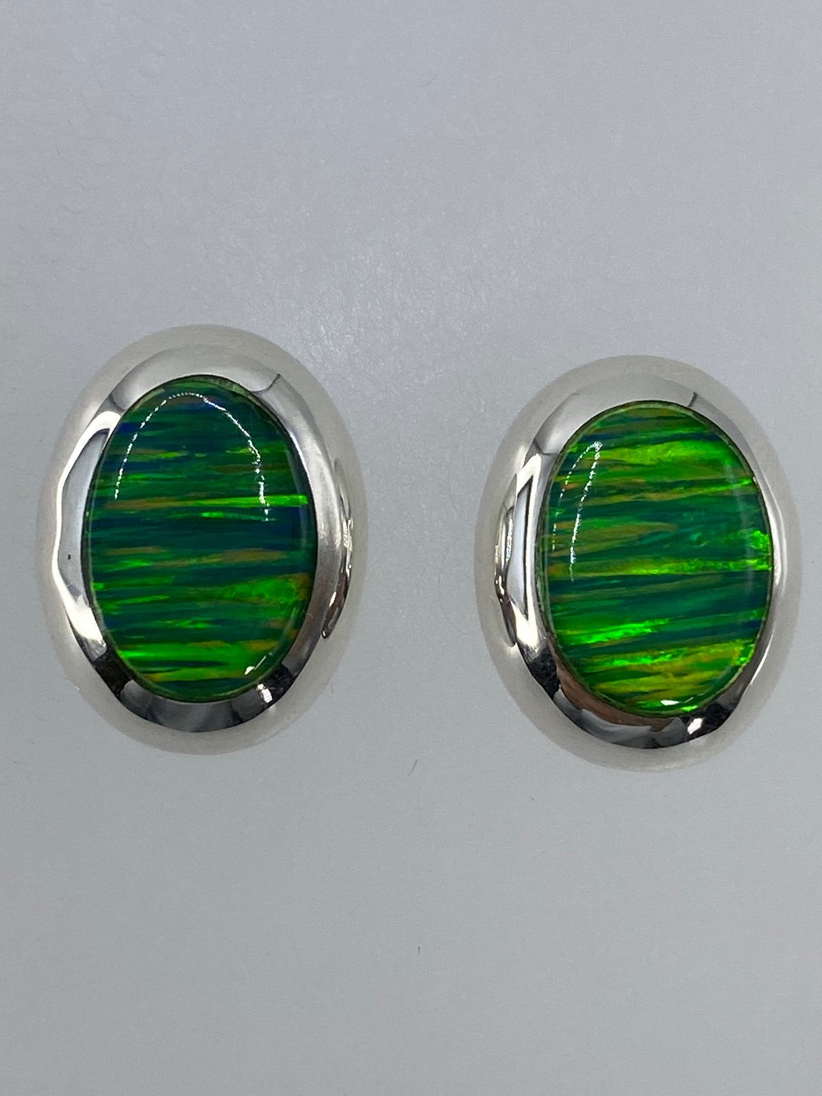 Par de aretes de plata con ópalo de fuego verde limón engastado, sobre fondo blanco