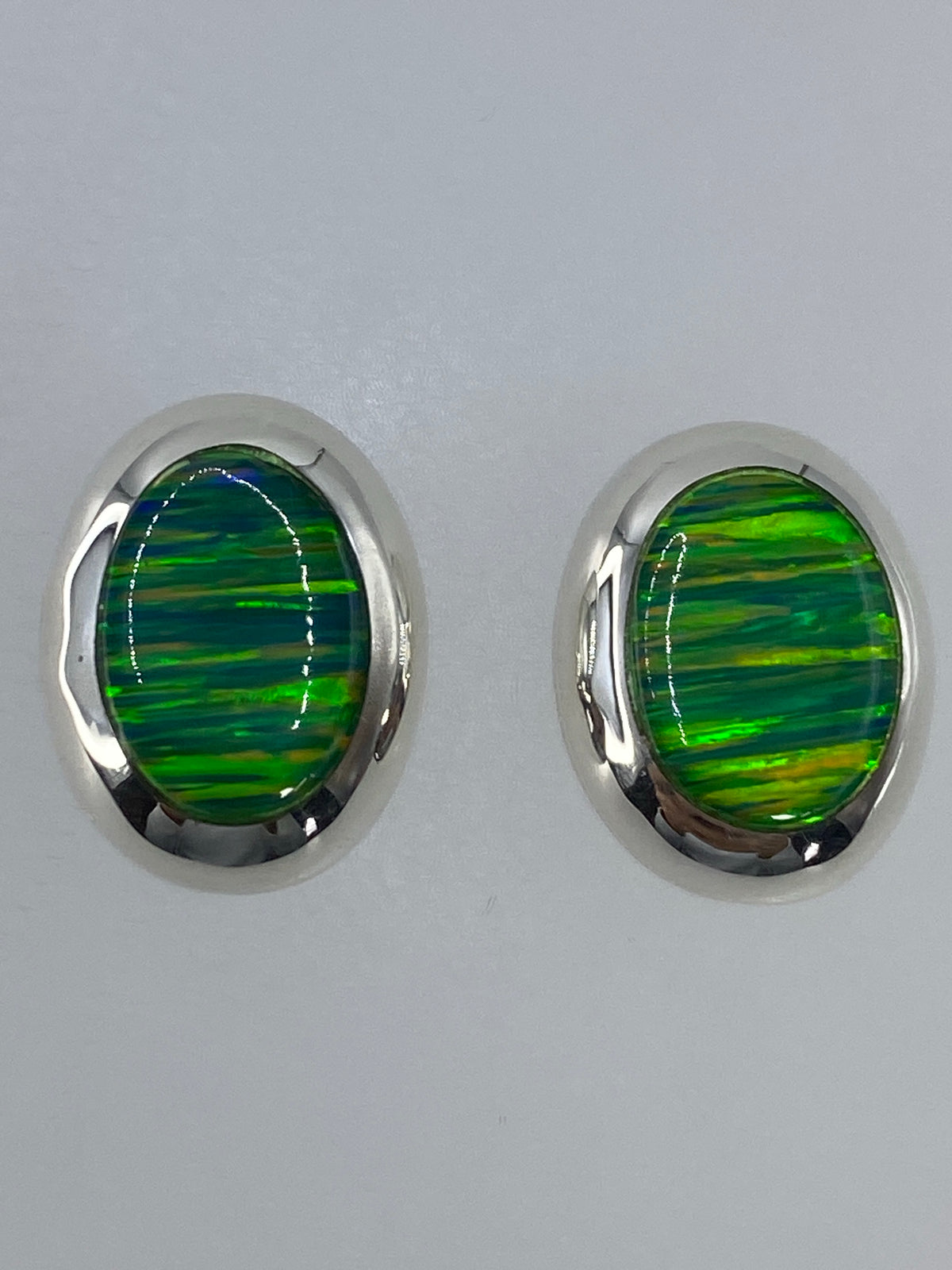 Detalle frontal de los aretes mostrando el color verde limón del ópalo de fuego