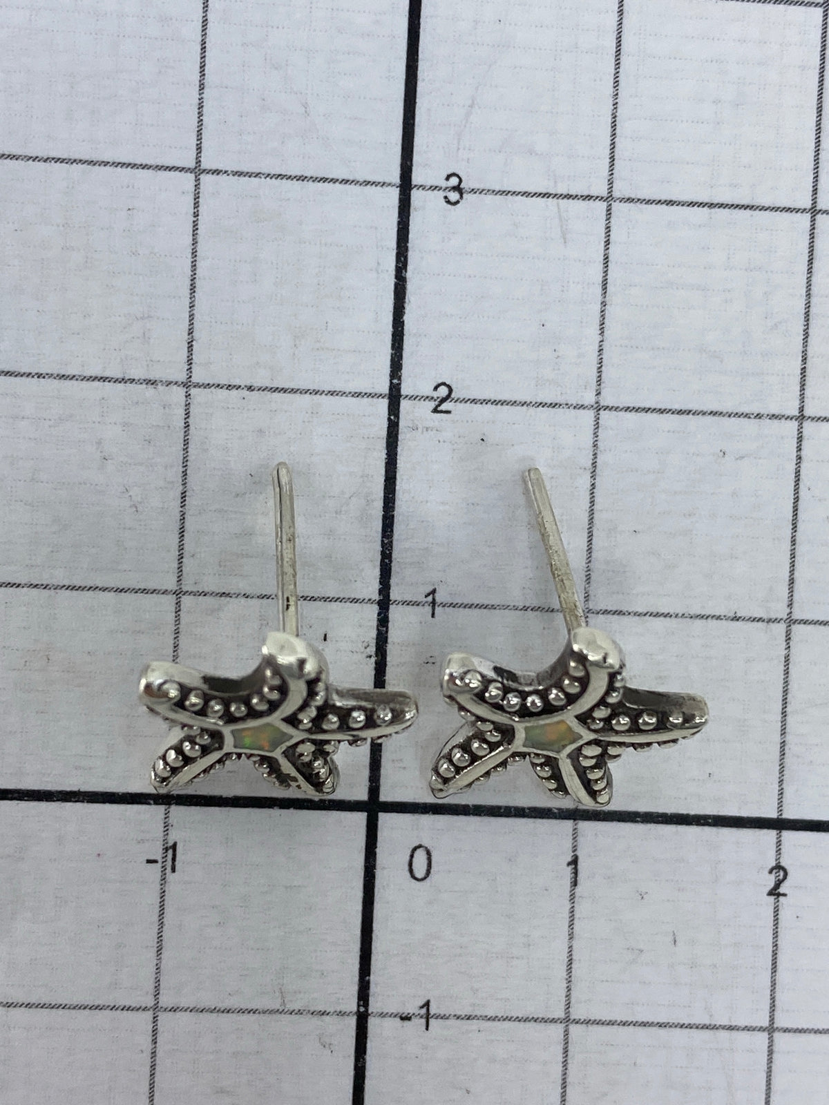 Aretes sobre medidor de centímetros mostrando el largo de 1.7 cm