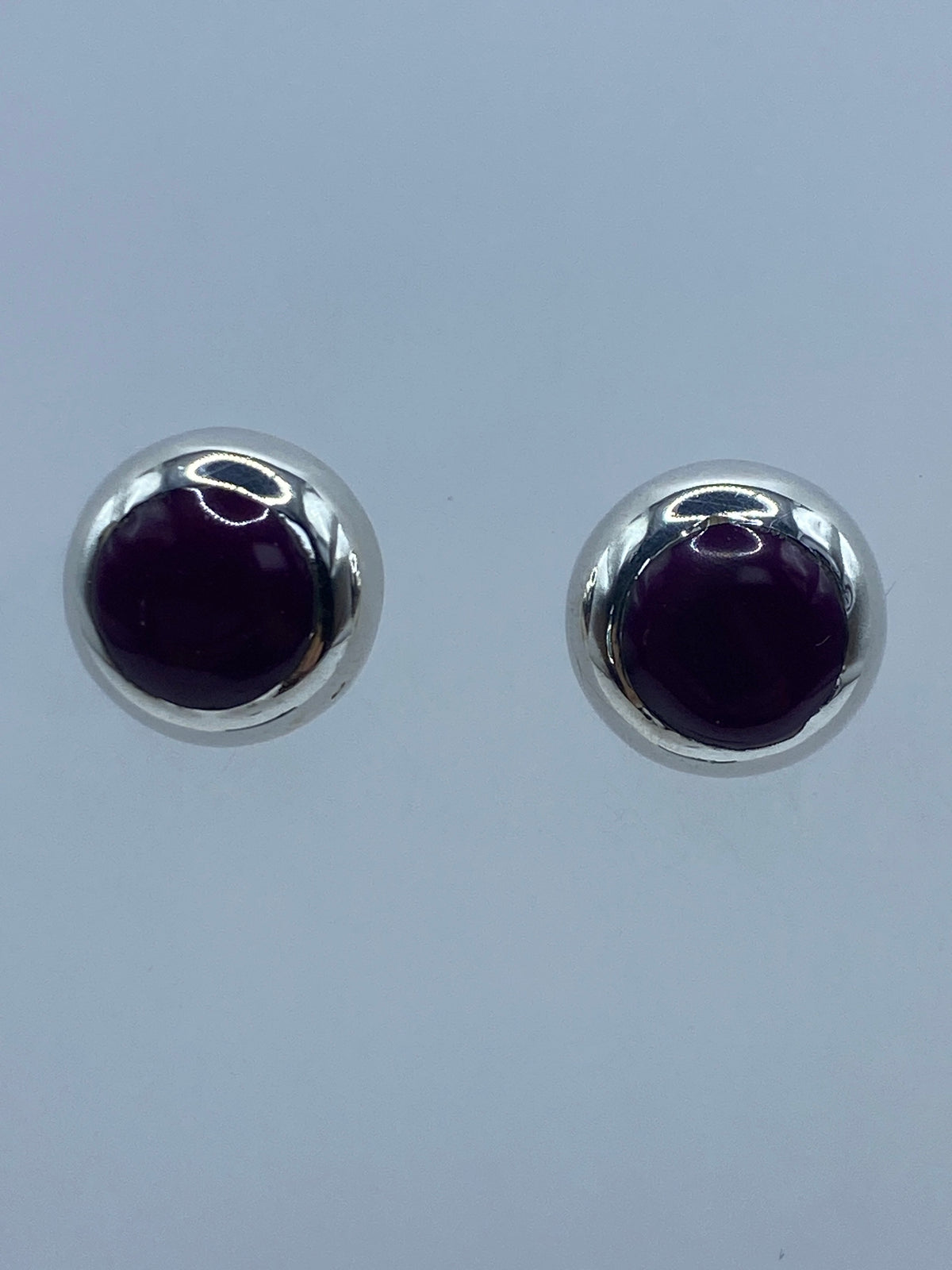 Par de aretes de plata con piedra morada redonda engastada a mano