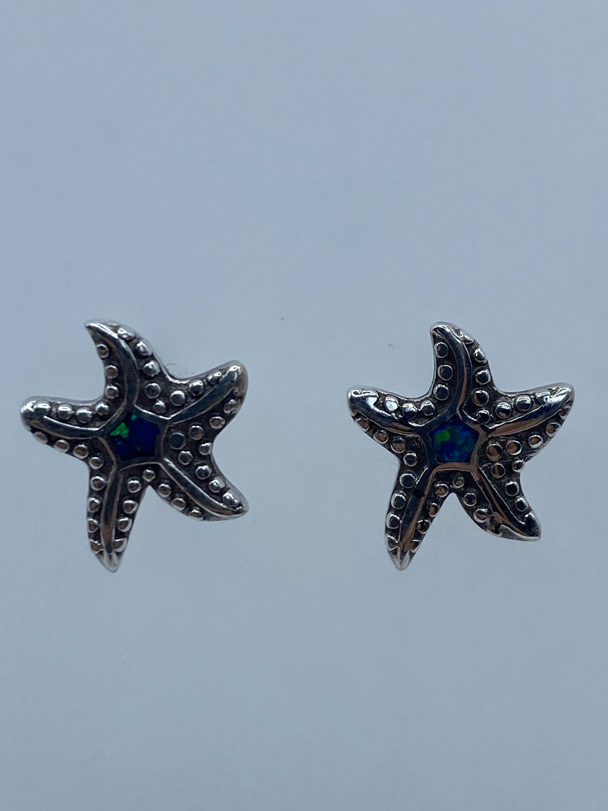 Par de aretes de plata en forma de estrella de mar con ópalo de fuego azul en el centro