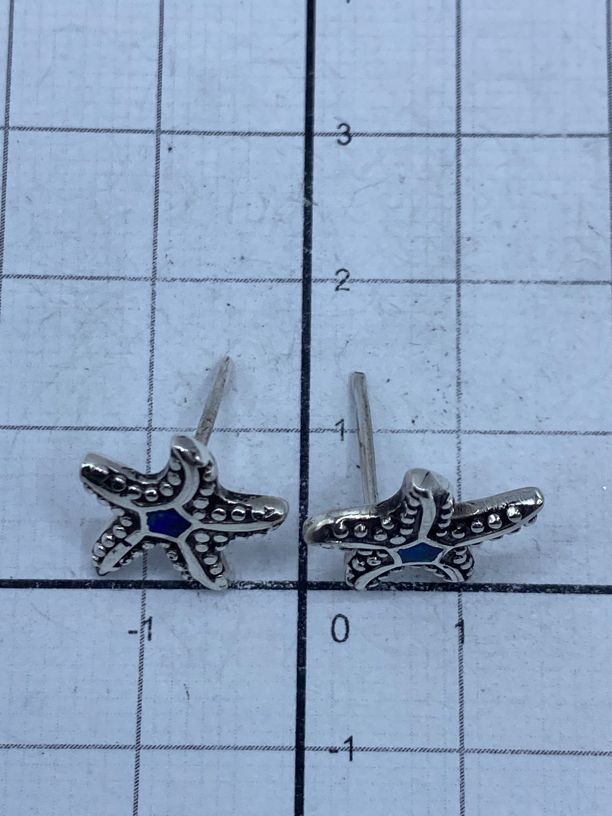 Aretes sobre escala de medición mostrando el tamaño de 1.2 cm