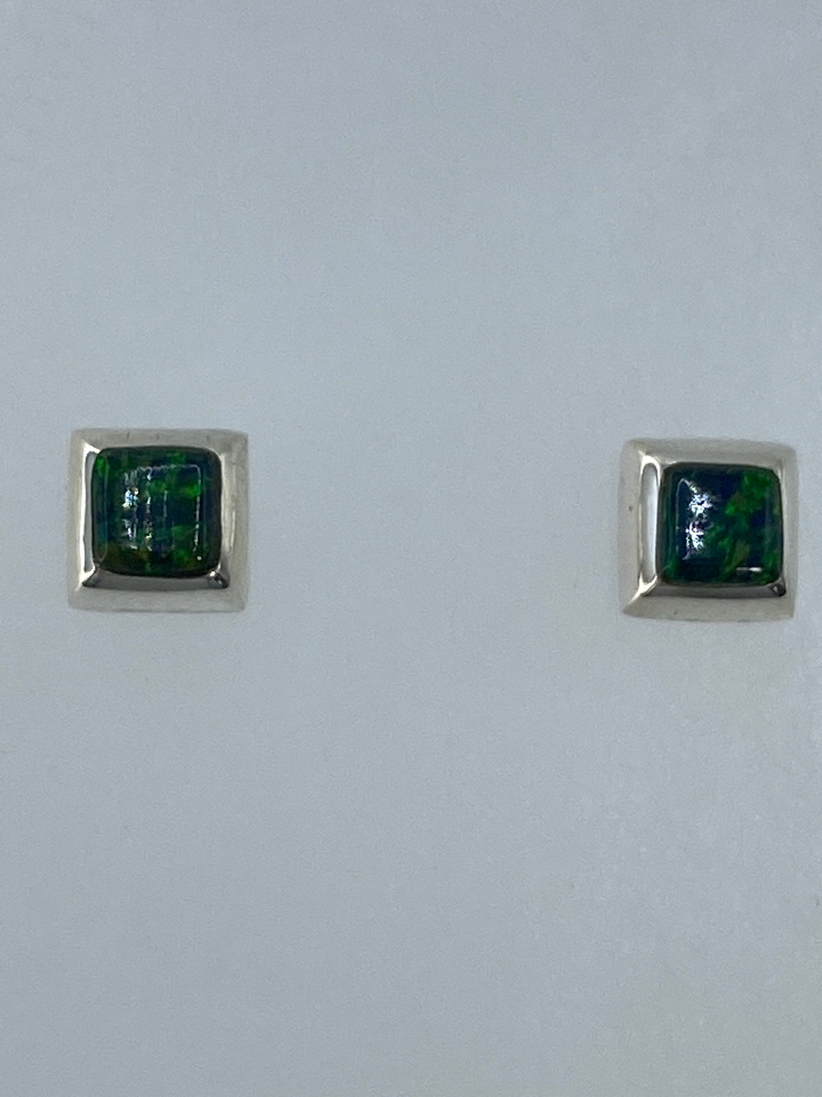 Par de aretes de plata con ópalo de fuego verde engastado, vistos de frente