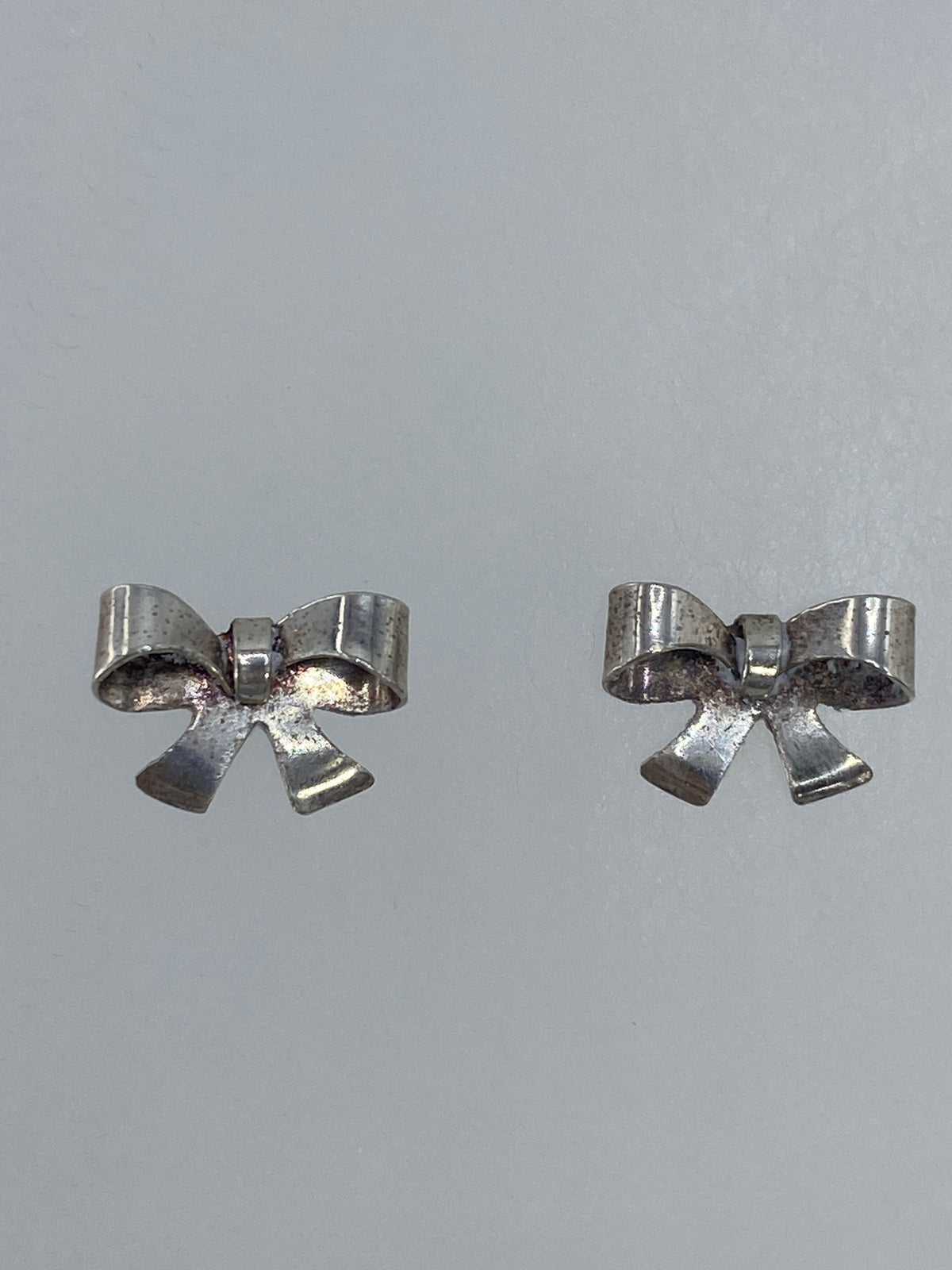Aretes de moño de plata con cierre de poste, vista frontal