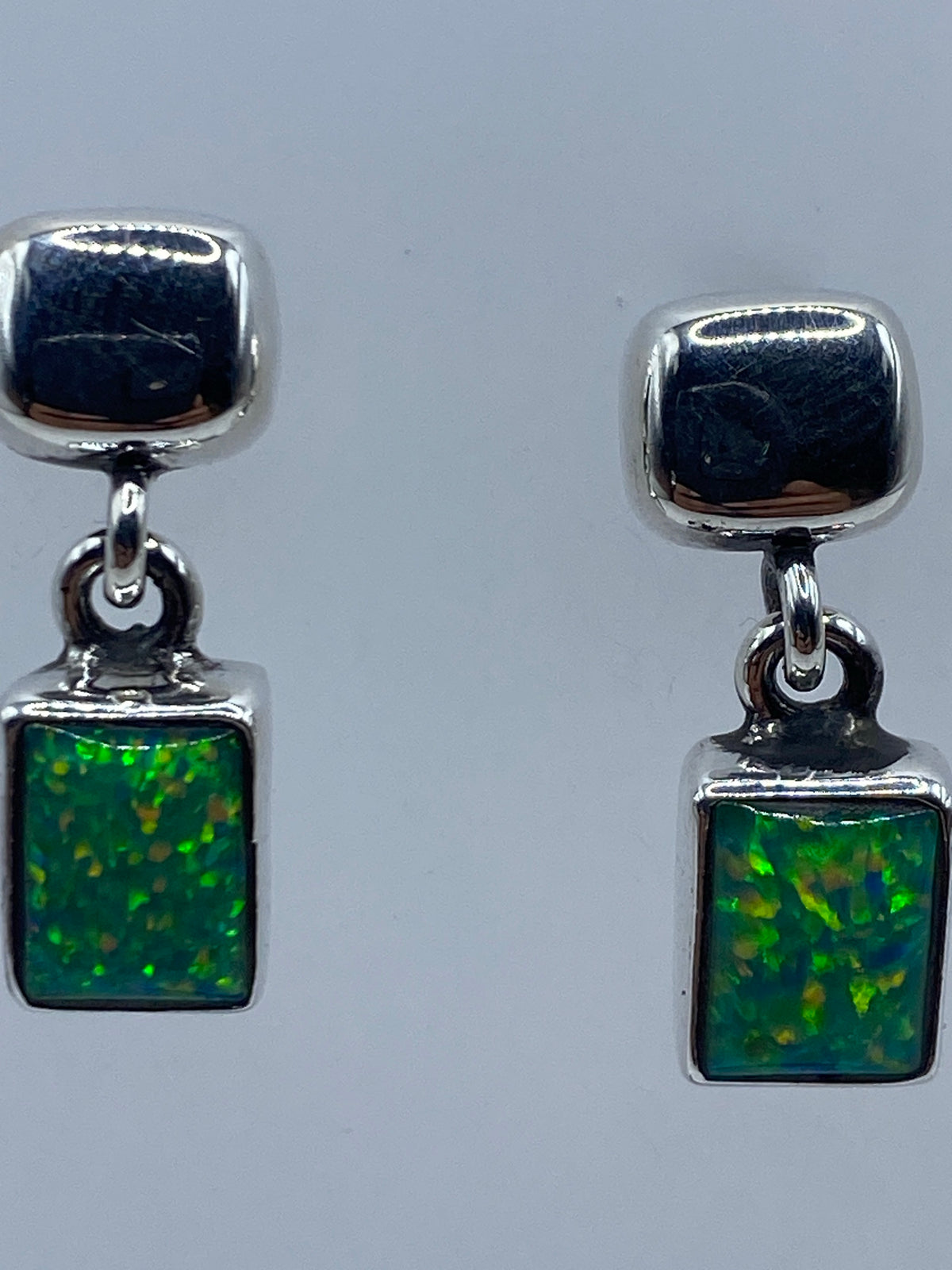 Aretes colgando con el cierre de poste y tuerca de plata visible