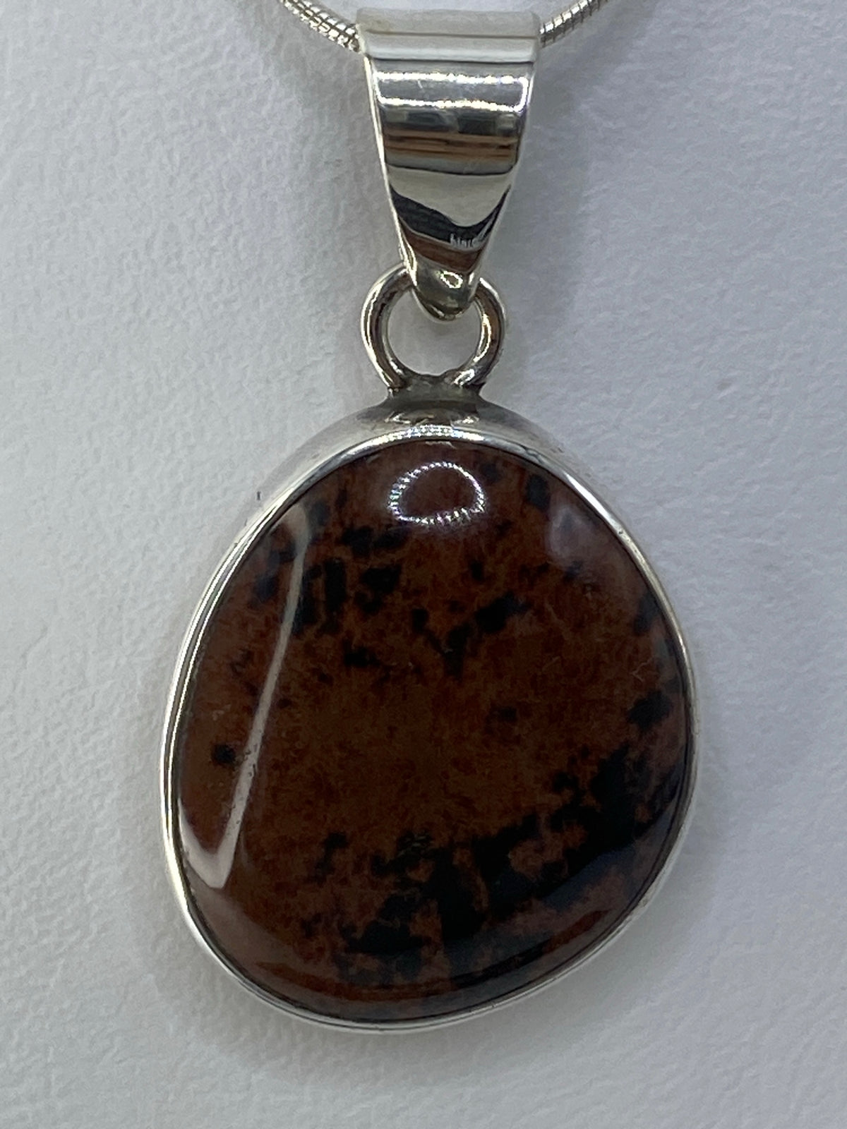Dije de plata 950 con piedra multicolor engastada, colgando de una cadena plateada