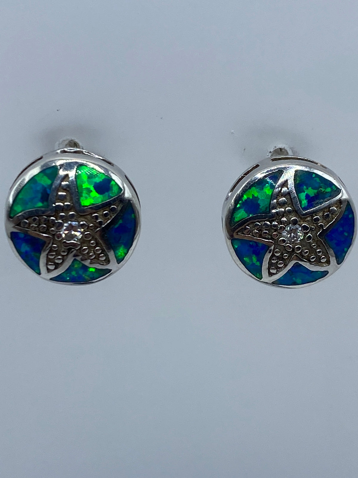 Arete individual mostrando el color azul del ópalo de fuego y el engaste en plata