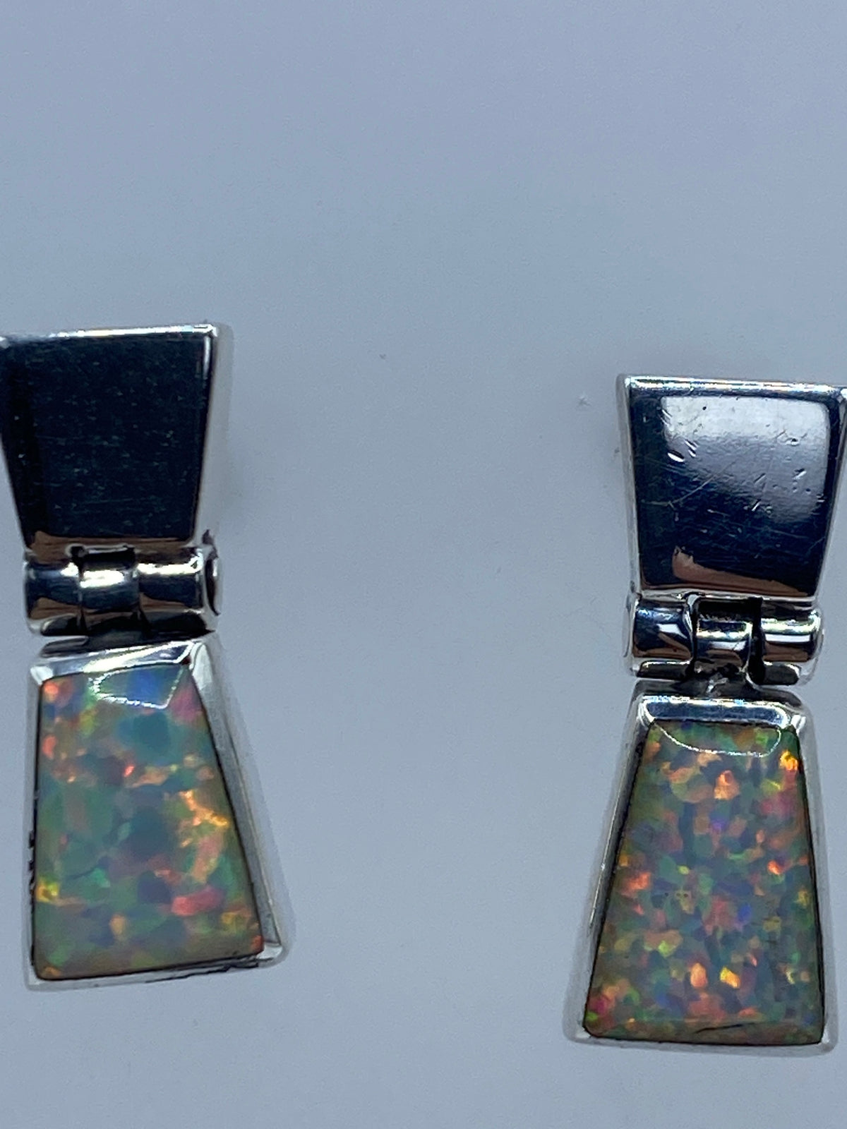 Aretes ópalo de fuego vistos de frente mostrando el juego de luz naranja y verde