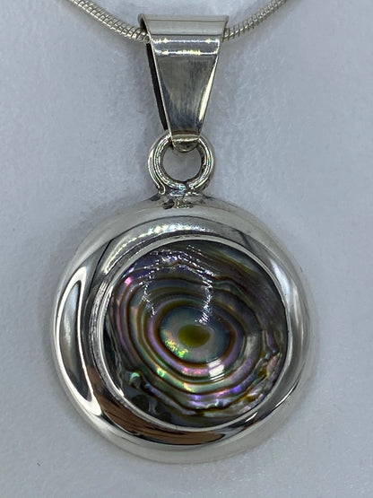 Dije de plata 925 con piedra multicolor reflejando luz, colgado de cadena de plata