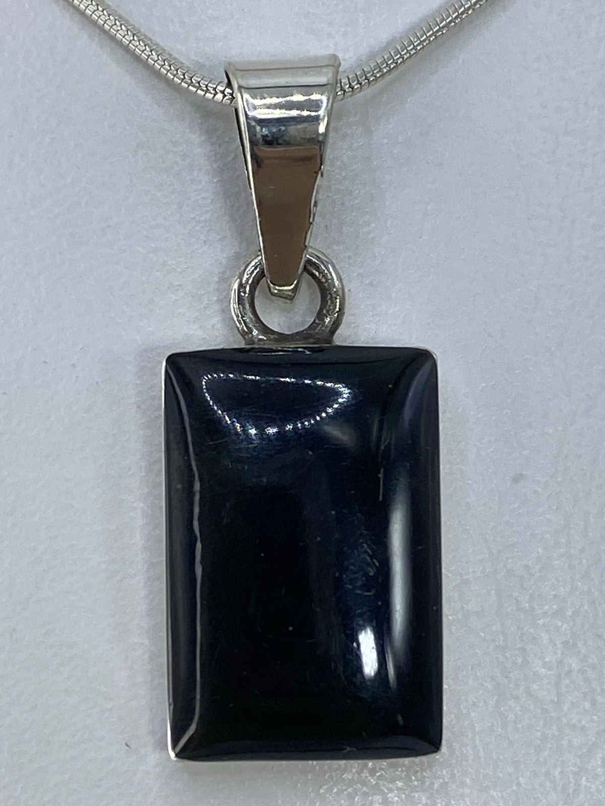 Dije de plata 950 con ónix negro pulido, rectangular, colgado de cadena de plata con brillo