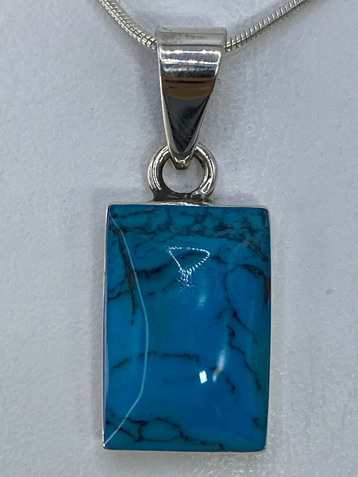 Dije de plata 950 con turquesa azul cielo, rectangular, sobre cadena plateada