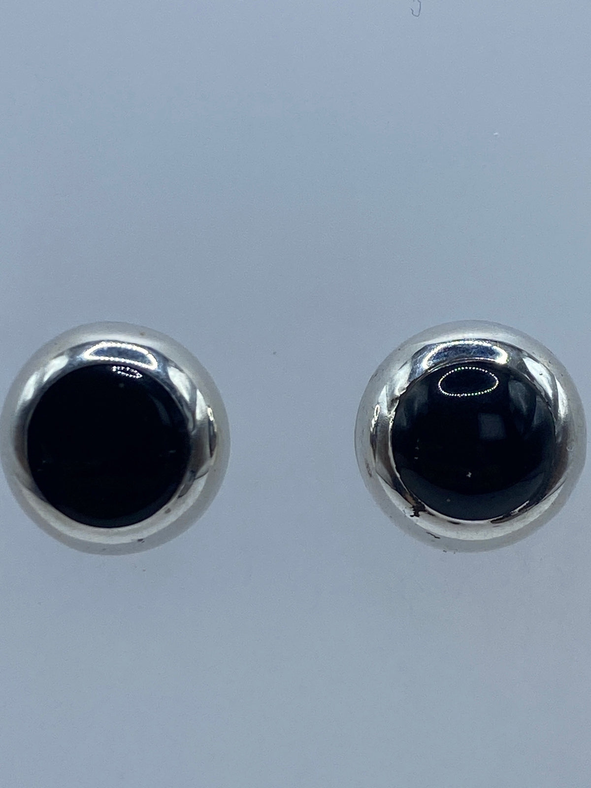 Aretes de ónix en la mano, mostrando el tamaño minimalista de 1.5 cm