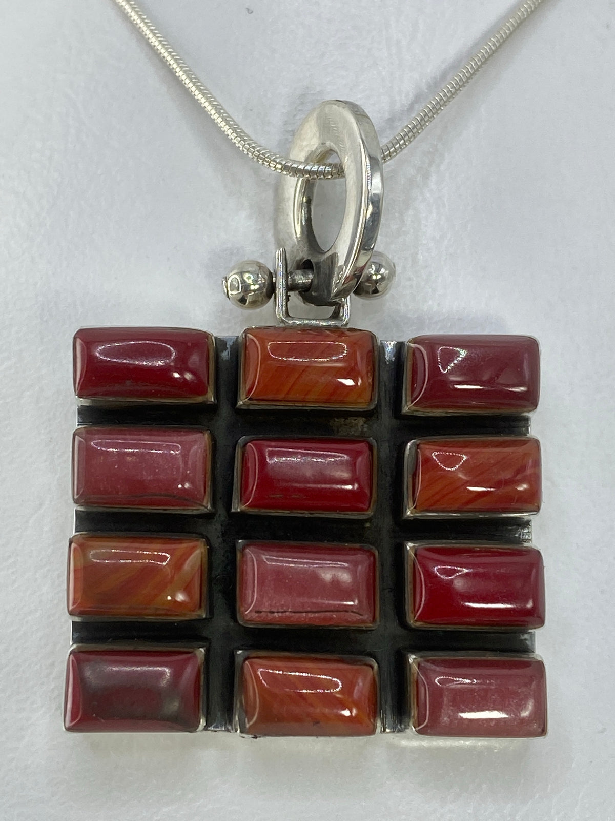 Dije de plata 925 con incrustación multicolor en tonos rojo, naranja, violeta y vino