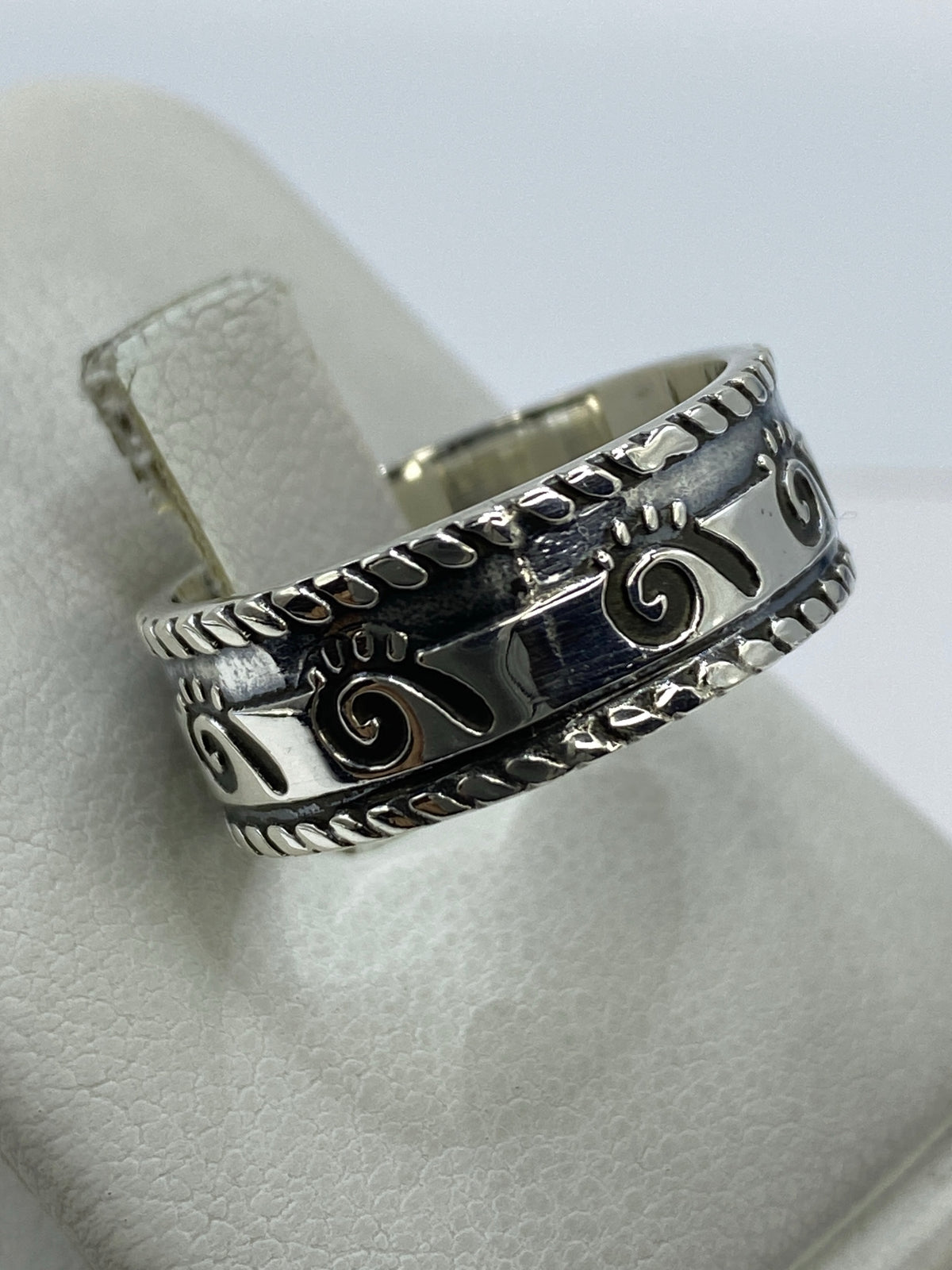 Anillo repujado unisex visto en la mano, mostrando el acabado pulido
