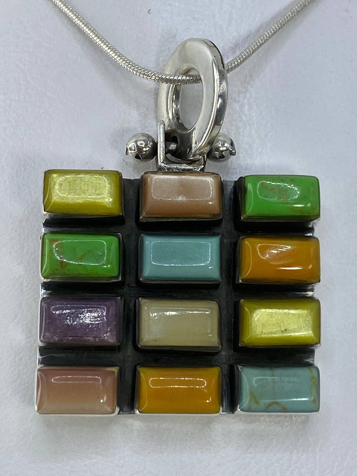 Dije de plata con incrustación de piedras multicolor en patrón 3×4, vista frontal