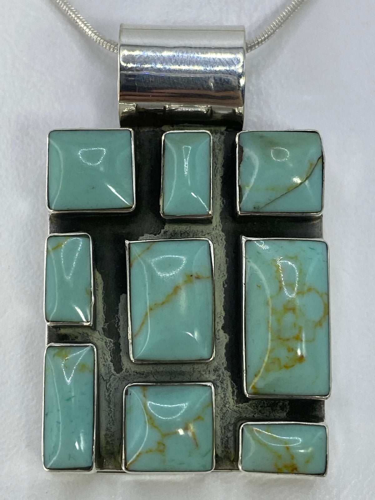 Dije de plata 925 con piedra engastada colgando de cadena de serpentín