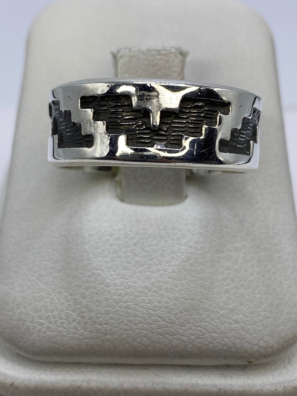 Anillo de plata repujado con diseño geométrico prehispánico, vista frontal en dedo