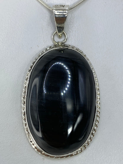 Dije de plata 950 con onix negro pulido, colgando en cadena serpentina