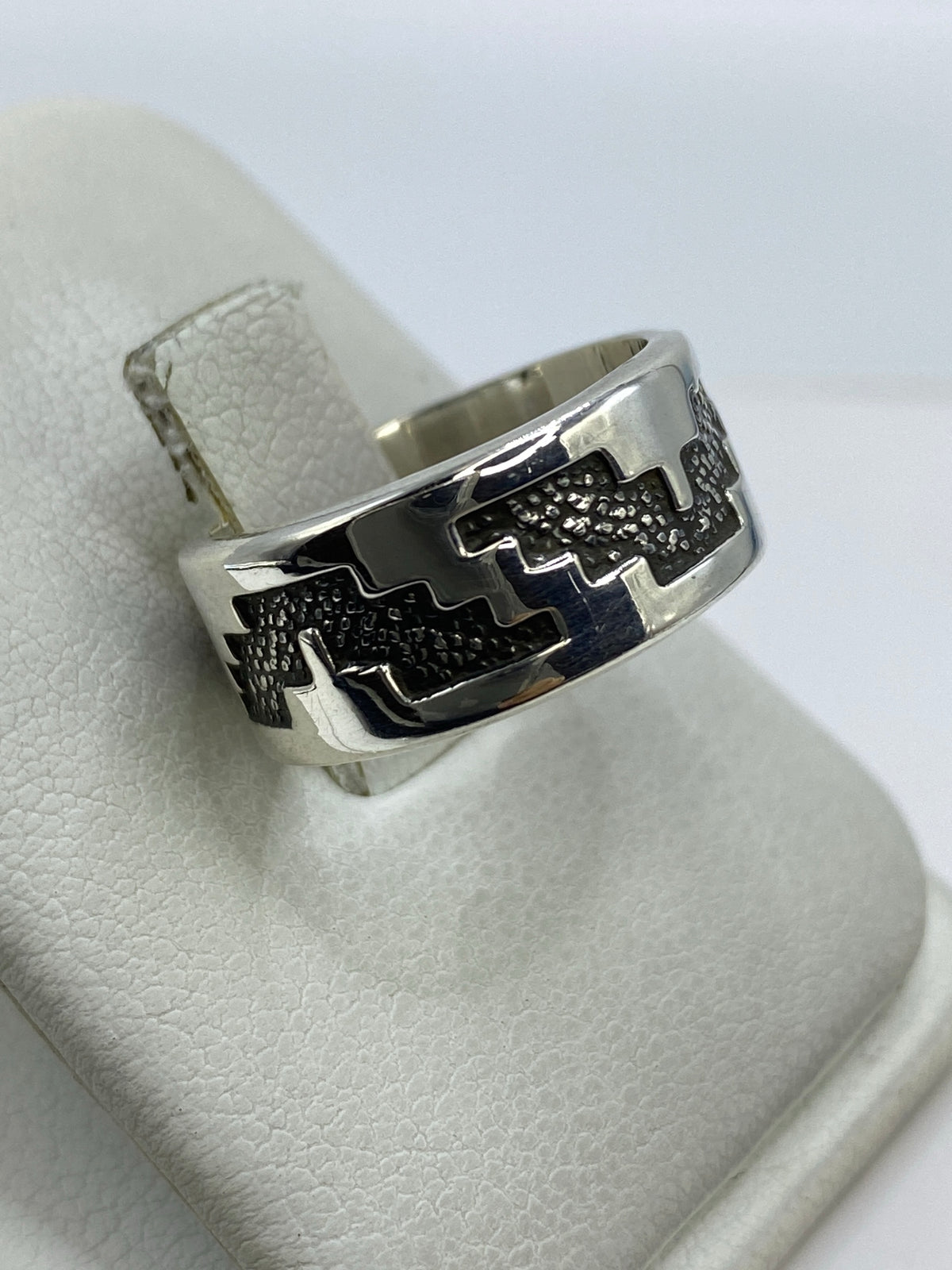 Detalle del repujado a mano — líneas en relieve del anillo de plata