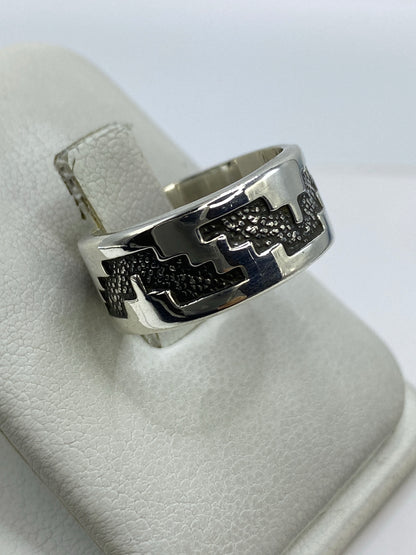 Detalle del repujado a mano — líneas en relieve del anillo de plata