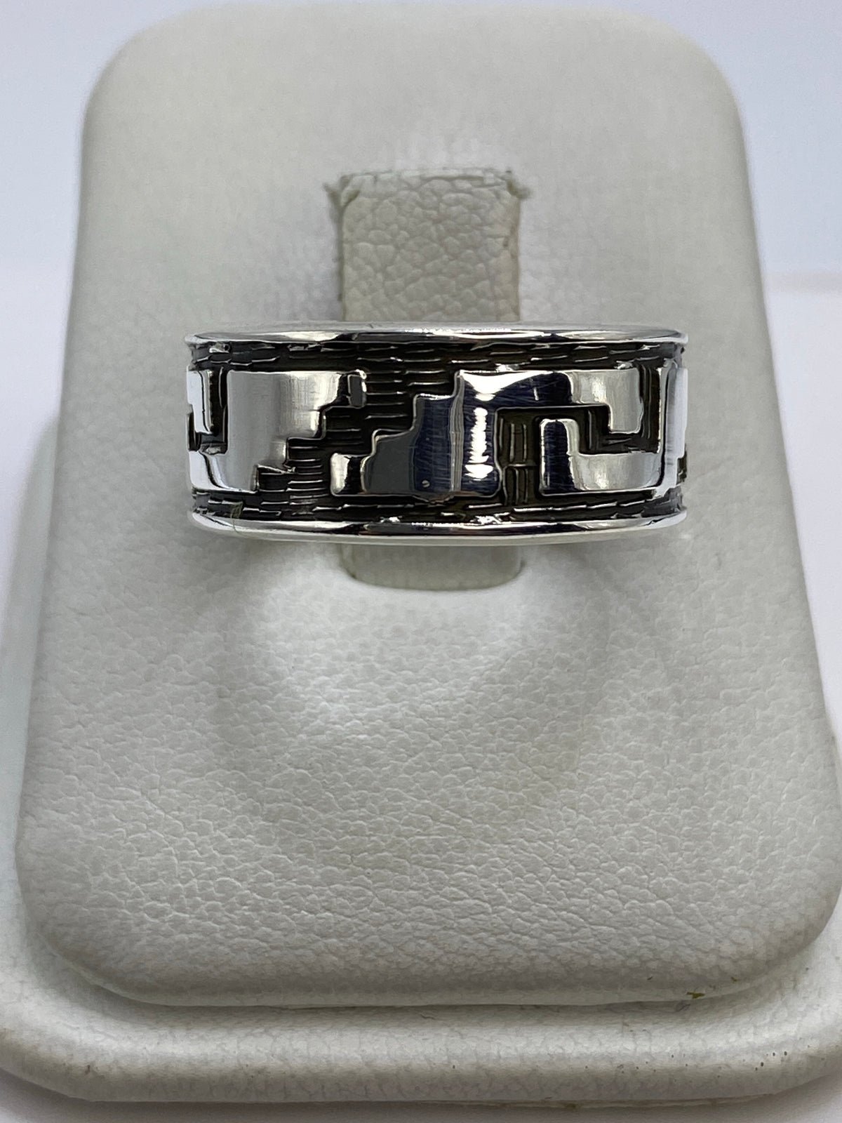 Anillo de plata repujado con patrón geométrico en relieve en mano de hombre