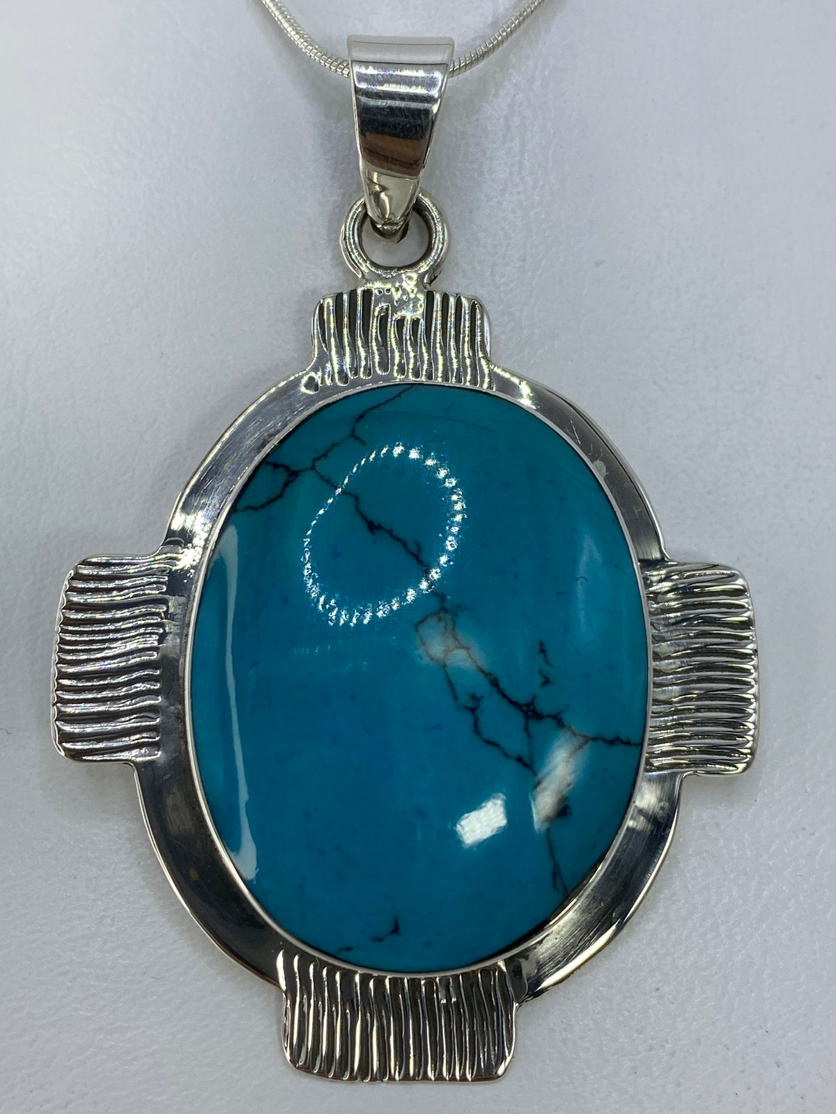 Detalle de la turquesa natural azul cielo y el engaste a mano en plata 950