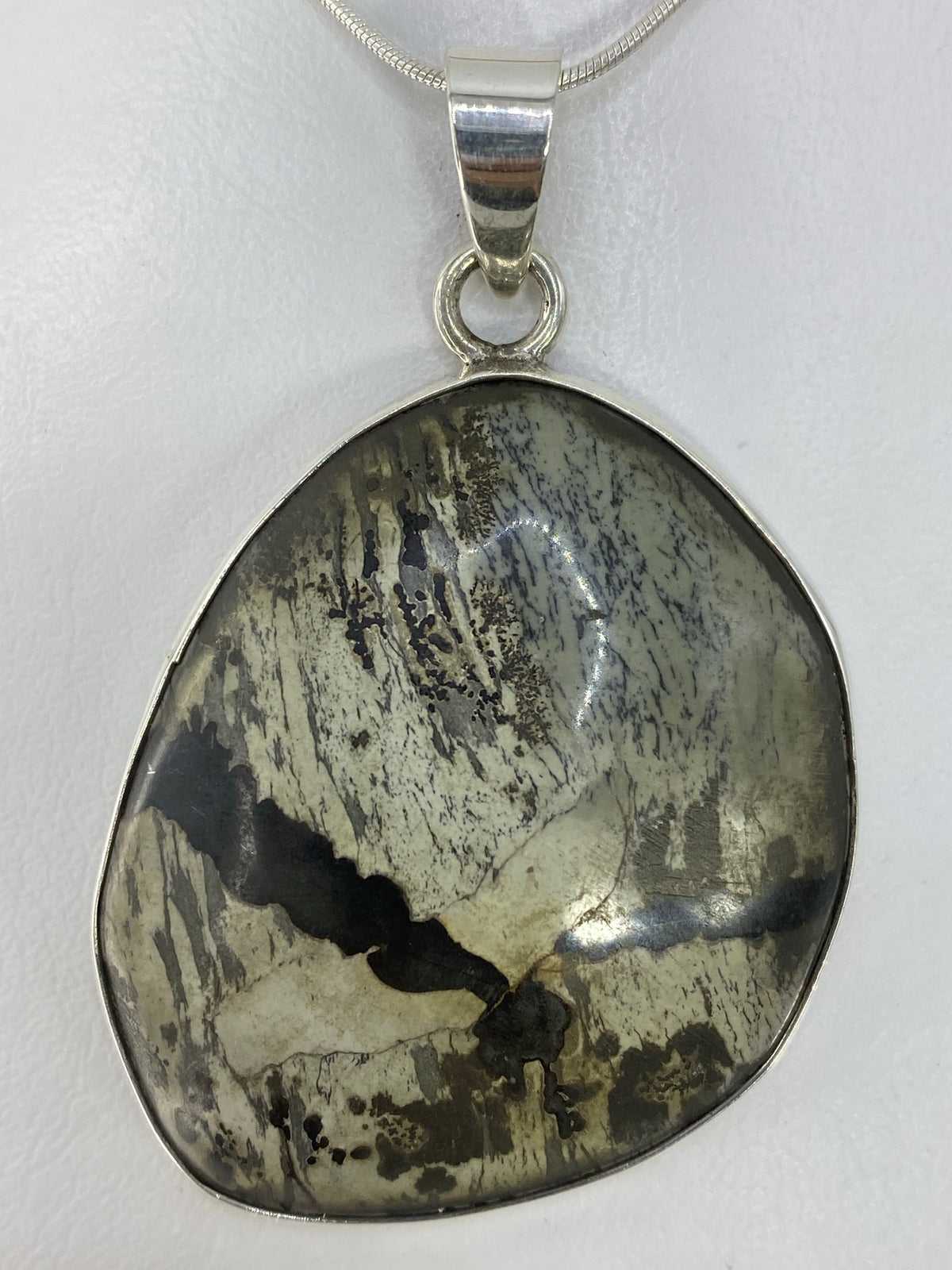 Detalle de la incrustación de piedra gris y negra en el dije de plata